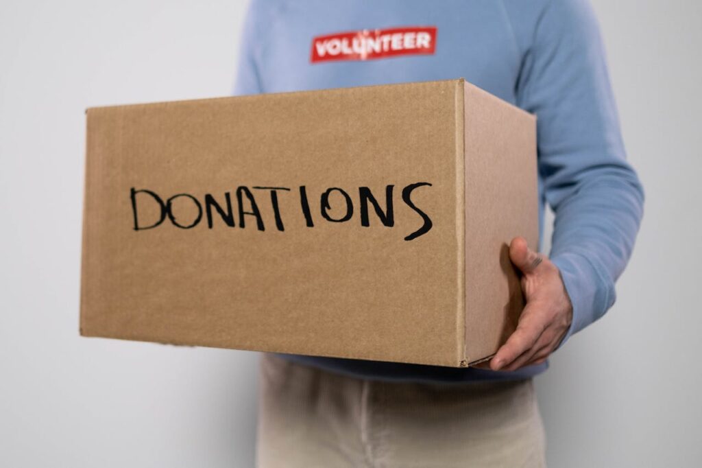 pexels photo 6591164 Close-up of a volunteer in a blue sweater holding a donation box. Concept of charity and volunteerism.